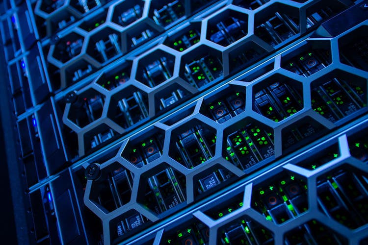 Image shows a close-up view of a modern server rack illuminated by blue LEDs, showcasing the intricate design of technology equipment and electronic components.