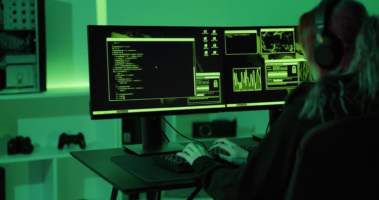 Female cyber security hacker making penetration code or malware to exploit zero-day vulnerability in program or system. Hacking on PC in a dark green room.